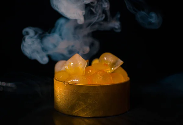 Ice in a golden box with smoke, colorful smoke, blue smoke, gray smoke, ice in syrup, delicious ice. space picture on dark background