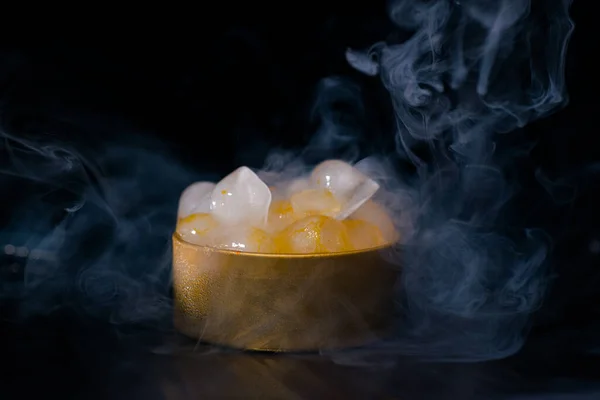 Ice in a golden box with smoke, colorful smoke, blue smoke, gray smoke, ice in syrup, delicious ice. space picture on dark background
