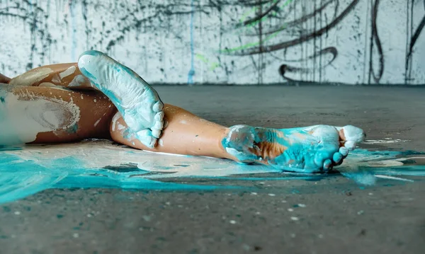 スタジオの床に横たわっているセクシーな若い芸術的に抽象的な女性の美しい足と足 オレンジ 青とターコイズペイントのバレリーナ 創造的なボディアート絵画 コピースペース — ストック写真