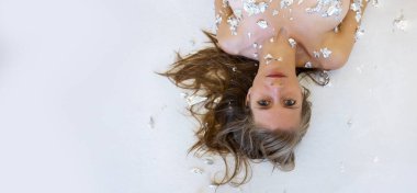 Geniş panorama afişi, alüminyum metalik konfetiyle genç, seksi, çıplak bir kadının baş aşağı portresi ve omuzları.