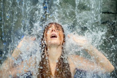 Güzel, genç, seksi, kızıl saçlı kadın. Ağzı açık, Spa Sağlık 'taki şelalenin akan suyunun tadını çıkarıyor. Düşen suyu hisset, kopyala.