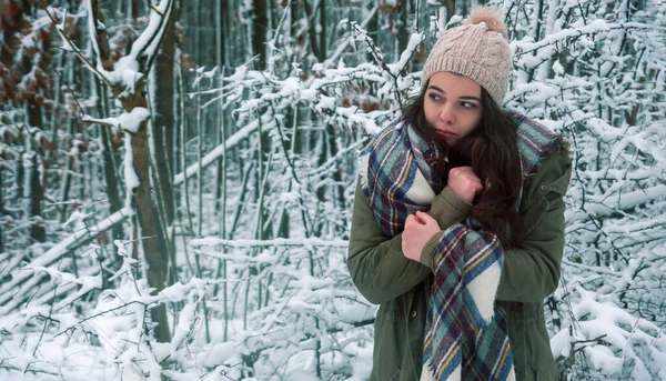 美丽的年轻冰冷的少女画像 戴着围巾 头戴针织的帽子 在雪白的圣诞森林里揉搓着冰冷的双手 复制空间 — 图库照片