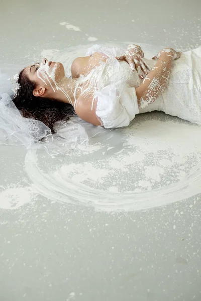 portrait and upper body of a beautiful young artistically abstract painted woman, bride, in wedding dress with white paint, creative, abstract body art, on the floor in the studio, copy space