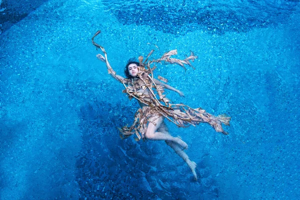 一个年轻貌美的性感女子优雅地在干枯的香蕉树树叶中轻松自在地漂浮着 碧绿的碧水在游泳池里 复制着空间 — 图库照片