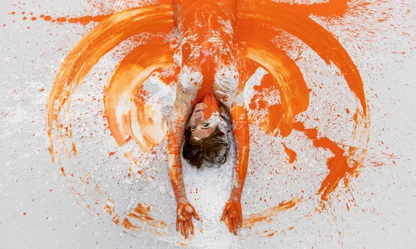 年轻性感的裸体孕妇的画像和上半身 涂着橙色的红头发女人 装饰华丽 躺在工作室的地板上 胳膊像天使的翅膀一样画着大大的圆圈 复制空间 — 图库照片