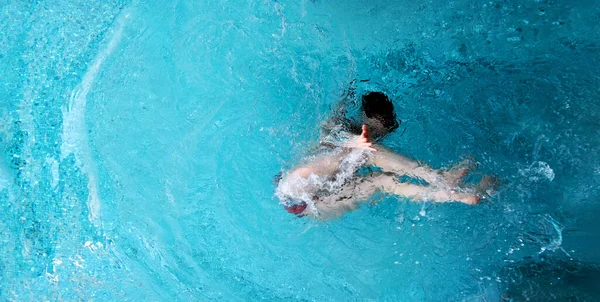 Turkuaz kaplıcalı seksi bikinili genç bayana yukarıdan bir manzara. Suyun altında eğleniyor ve size uzanıyor ve sizi davet ediyor.