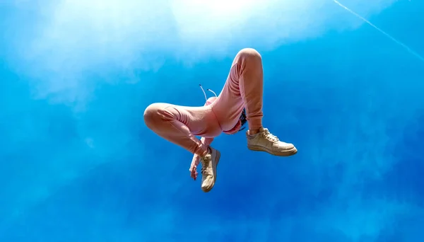 view from below to young beautiful woman in pink sports suit jumps full of happiness joy and freedom in a joyful leap into the bright sunny blue sky, copy space