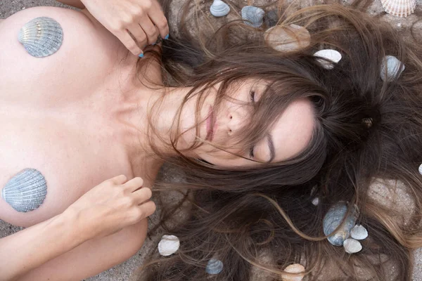俯瞰美丽而性感的年轻裸露的黑发女子画像 在海滩上躺着贝壳 满脸乱蓬蓬的头发 — 图库照片