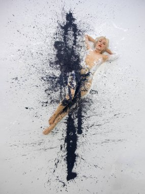 Sanatsal olarak soyut, siyah beyaz boyalı çıplak bir kadın. Stüdyoda dizayn edilmiş zeminde uzanıyor.