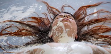 Portre, kafa, üst vücut, göğüsler ve kollar beyaz renkli, çıplak seksi bir kadın stüdyonun gri mavi zemininde yatıyor. Yaratıcı dışavurumcu soyut vücut boyama sanatı, kopyalama alanı