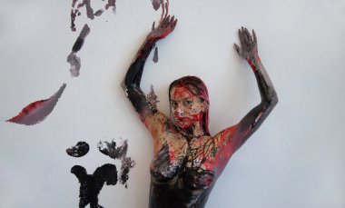 Siyah beyaz boyalı genç bir kadının sanatsal portresi. Stüdyoda beyaz duvarın önünde yuvarlanıyor. Renkli resimler bırakıyor.