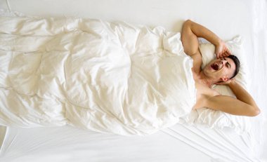 Çekici, genç, seksi, baştan çıkarıcı, esmer, erkeksi, kahverengi saçlı, yatakta gerinen, fotokopi çeken bir erkek.