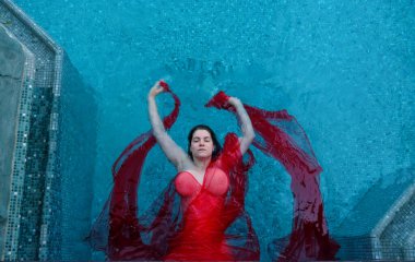 Bir kadın, mavi suyla çok güzel zıtlaşan kırmızı bir kumaşa sarılı bir havuzda huzur içinde yüzüyor. Onun barışçıl ifadesi ve zarif duruşu bir sükunet ve zarafet hissi uyandırıyor..