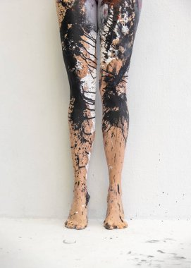 Güzel bacakları ve ayakları olan seksi çıplak kadın beyaz arka plana siyah, beyaz ve kahverengi boyayla kaplanmış, soyut boya çarpıcı ve sanatsal bir görsel efekt yaratıyor.