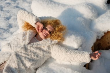 Neşeli, kızıl saçlı, beyaz örtülü seksi kadın yumuşak karın üzerinde neşe içinde yatıyor. Kış sahnesine karşı neşeli bir kontrastlık yaratıyor.