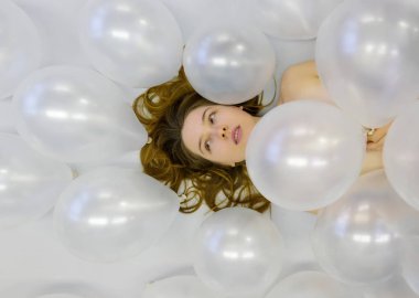Şehvetli kadın, yumuşak beyaz balonlarla çevrili yatar, dalgalı saçları ve nazik ifadesi rüya gibi ve ruhani bir atmosfer yaratır, zarafet, samimiyet ve sessiz bir güzellik uyandırır..