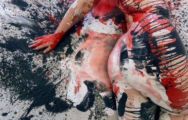 Kırmızı, siyah ve beyaz renkli gerçekçi boya lekeleriyle etkileşime geçen boyalı bir kadın vücudunun soyut yakın çekimi. Modelin kolu ve kalçası, yerdeki kalın darbelerle harmanlanır..