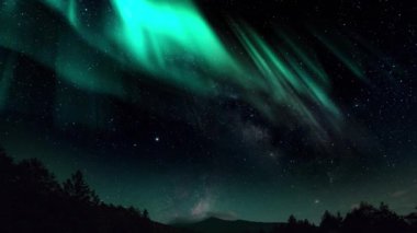Aurora Borealis Samanyolu Galaksisi ile iç içe geçiyor. Kuzey Işıkları Zaman Hızı Güneş Rüzgarı. Göksel Işıkların Dansı. Kuzey ışıkları, yeşil ve mor renkte parlayan güneş rüzgârlarıyla dönüyor.