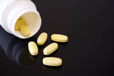 Haplar siyah arka planda ilaç şişesinden dökülüyor.