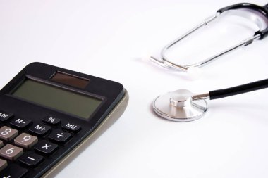 Beyaz arkaplanda steteskop ve hesap makinesi, kapatın