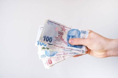 Gri arkaplanda Türk lirası tutan erkek el