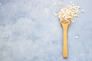 Mavi arka planda ahşap kaşıklı yulaf gevrekleri