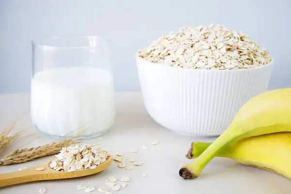 Kasedeki yulaf gevreği, beyaz masada süt ve muz.