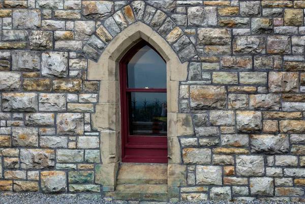 A small, beautiful gothic-style window on a stone castle wall