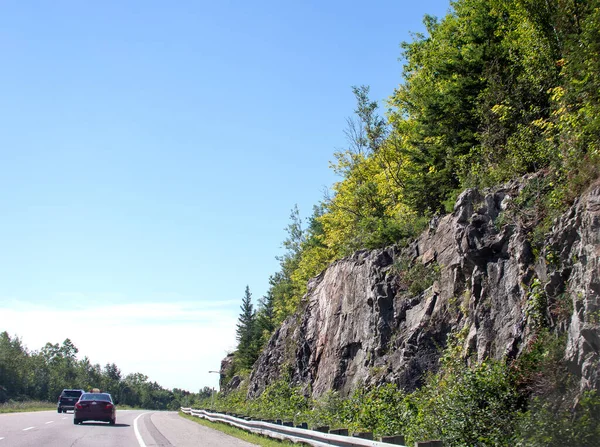 stock image Rocks overgrown with green bushes and trees along the road to Ontario