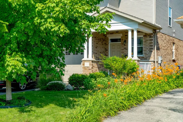 沿着绿色的草坪 房子的入口被绿色和橙色的百合花环绕着 — 图库照片