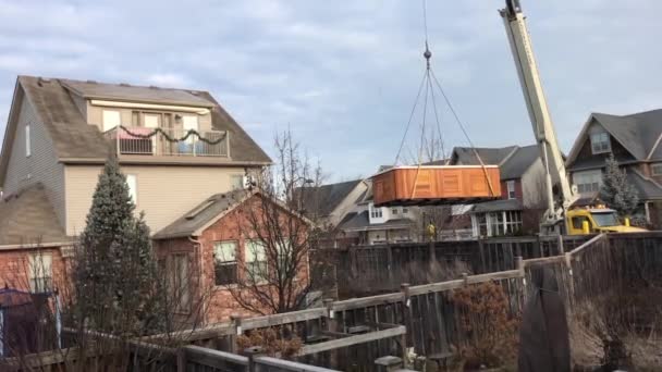一辆大卡车起重机站在路上 通过栅栏把大量的重物搬运到房子的院子里 — 图库视频影像