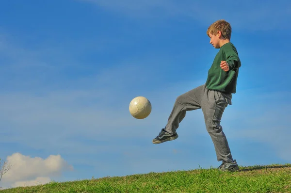 Junge Spielt Mit Ball Auf Einem Hügel Gegen Den Blauen Stockbild
