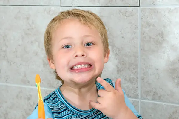 一个男孩拿着牙刷 向妈妈展示他刷牙的本事 图库图片