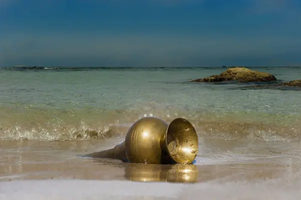 靠近海岸的海水中 青铜复古灯躺在沙滩上 图库图片