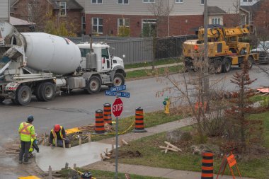 İşçiler kaldırımı tamir ettikten sonra taze betonu düzeltiyorlar