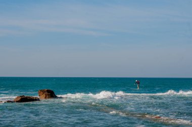Kürekli yalnız bir sörfçü sessiz ve sakin bir denizde süzülür.