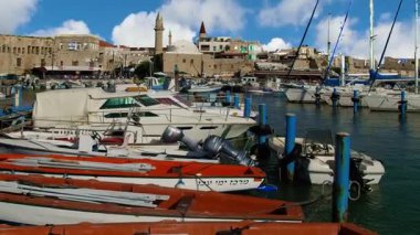 Acre antik şehrinde mavi gökyüzünün altındaki iskelede kırmızı kayıklar duruyor.