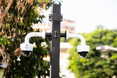 Selective focus to CCTV Camera with blurry green tree in the park.