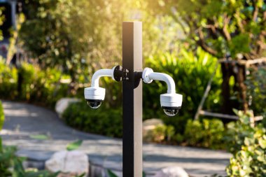 Selective focus to CCTV Camera with blurry green tree in the park.