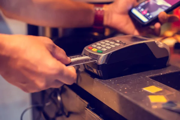 Selective focus to credit card reader with blurry hand put credit card In slot for payment, buy and sell products or service , the concept of payment without cash.