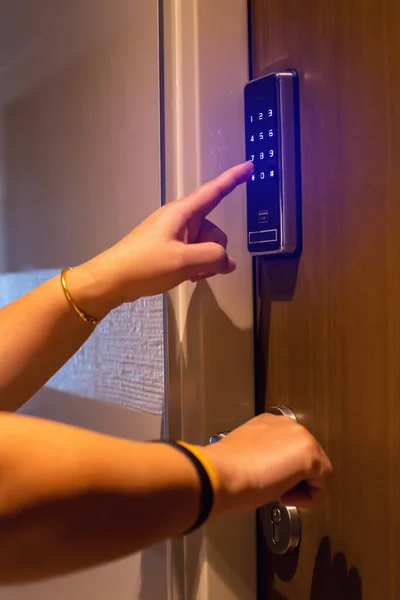 Female hand dials the access code on the digital door lock system by pressing a index finger on button, enters the code access to open door.