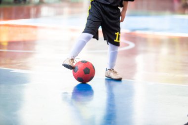 Bulanık çocuk futsal oyuncusuyla mavi kata seçici odak. Topu gol atmak için kontrol ediyor..