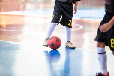 Futsal oynayan çocuk şut ve gol için topu kontrol ediyor. Kapalı spor salonu.