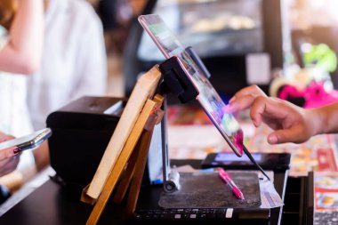 Tabletin kenarına seçici odak bulanık kasiyer kadrosuyla Kafe veya mağazadaki sayaç servisinden müşterilerin siparişlerini almak için tablet kullanarak.
