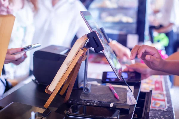 stock image Selective focus to edge of the tablet with blurry cashier staff using tablet to receive orders from customers at counter service in cafe or store.