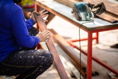 Tayland 'daki fabrikada zımpara kağıdıyla marangozun tahta yüzeyini düzleştirmeye odaklan. Zımpara kağıdıyla ahşabı zımparalayıp düzleştirmek.