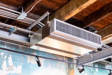 Tavana monte edilmiş kaset tipi klima ünitelerine seçici odak. Havalandırma sisteminin diğer kısımlarında asılı ışıklar ve vintage ofis veya vintage shop 'taki diğer inşaat parçaları var..