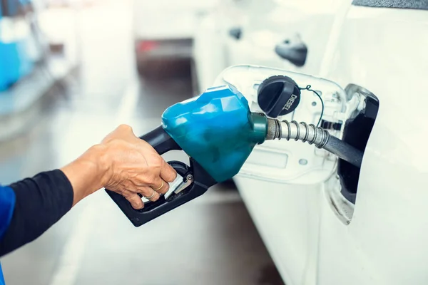 Hand refilling the white pickup truck with fuel at the gas station. Oil and gas energy. Fill a small truck with diesel fuel for transportation.