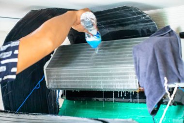 Evde ya da ofiste temizlik için temizleyici kullanan teknisyenin bulanık eliyle soğutma bobini paneline seçici odaklanma.