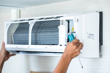 Evde ya da ofiste teknisyenlerin elinde bulanık tornavida bulunan klimaya seçici odaklanma.